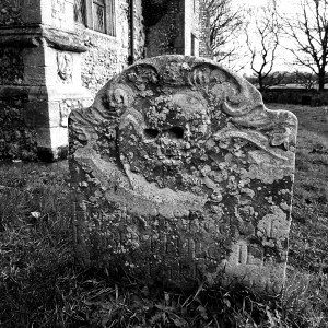 Black and white photograph of an old headstone, carved with a winged skull at Felbrigg Hall (National Trust) Norfolk. Copyright Lisa Tulfer 2020