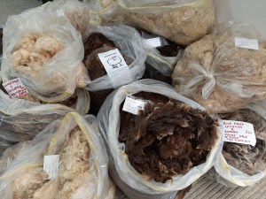 Sacks of sheep's fleeces in a range of natural colours.