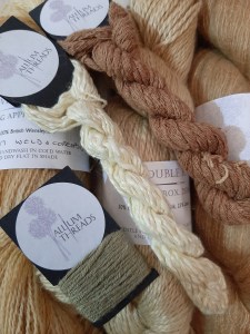 A selection of naturally-dyed yarns in shades of cream, wheat and green.